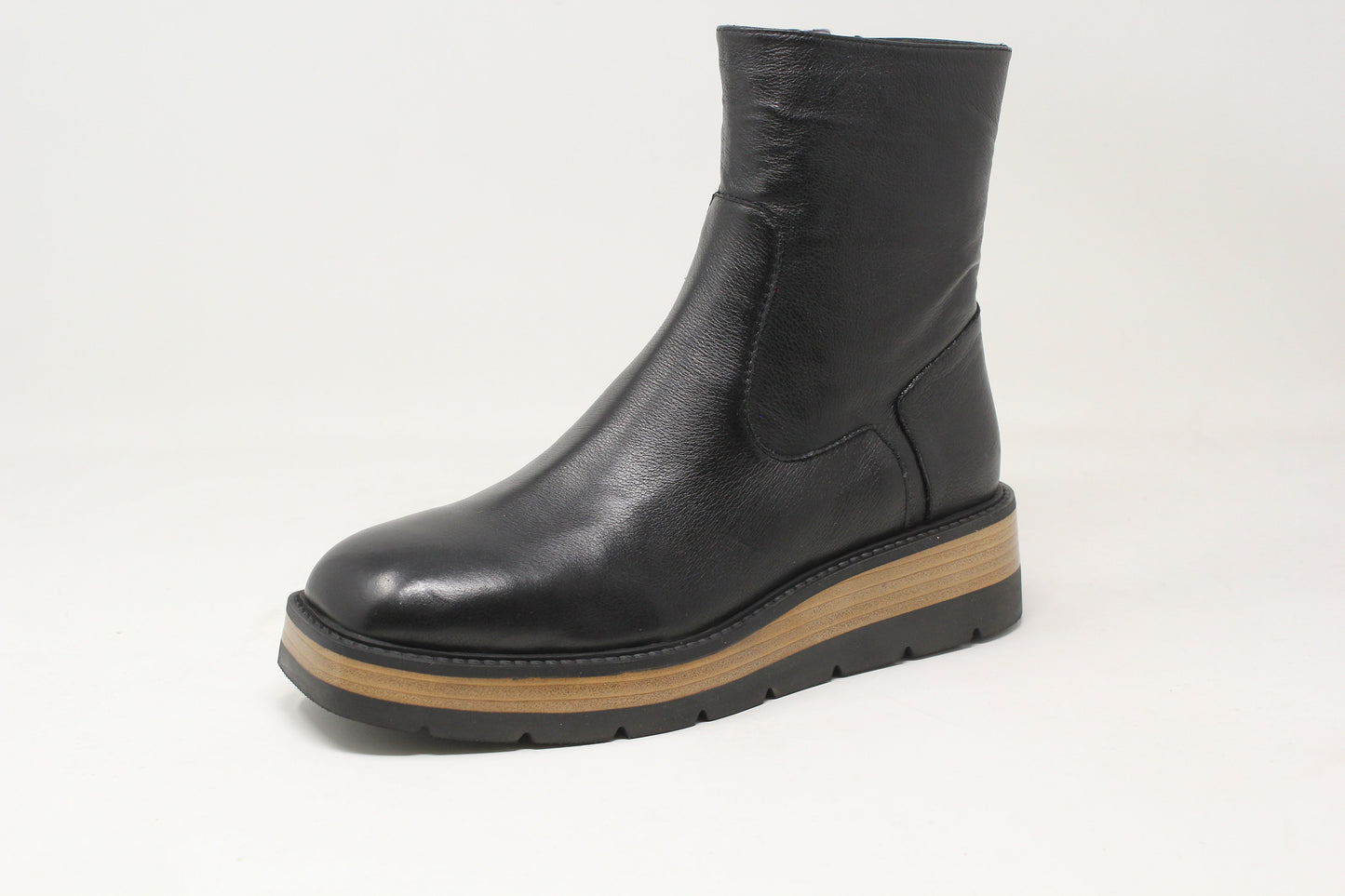 Black ankle boot with a brown sole on a light gray background